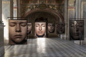 Pohled do hlavní lodi kostela s fotografiemi z cyklu Tváře fotografa Pavla Máry