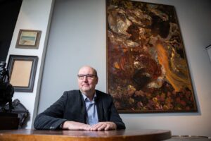 Tomáš Hejtmánek s obrazem Hra slunečních skvrn Karla Vítězstava Maška. Zašlé plátno vlastnoručně vyčistil.